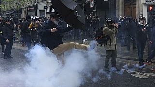A man kicks in a tear gas canister during a demonstration, Monday, May 1, 2023 in Paris.