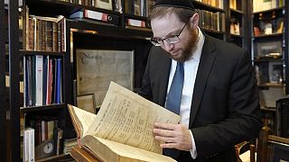 Rabbi Nicky Liss looks through items in a collection of memorabilia related to the history of British Jews, in London, Friday, April 28, 2023