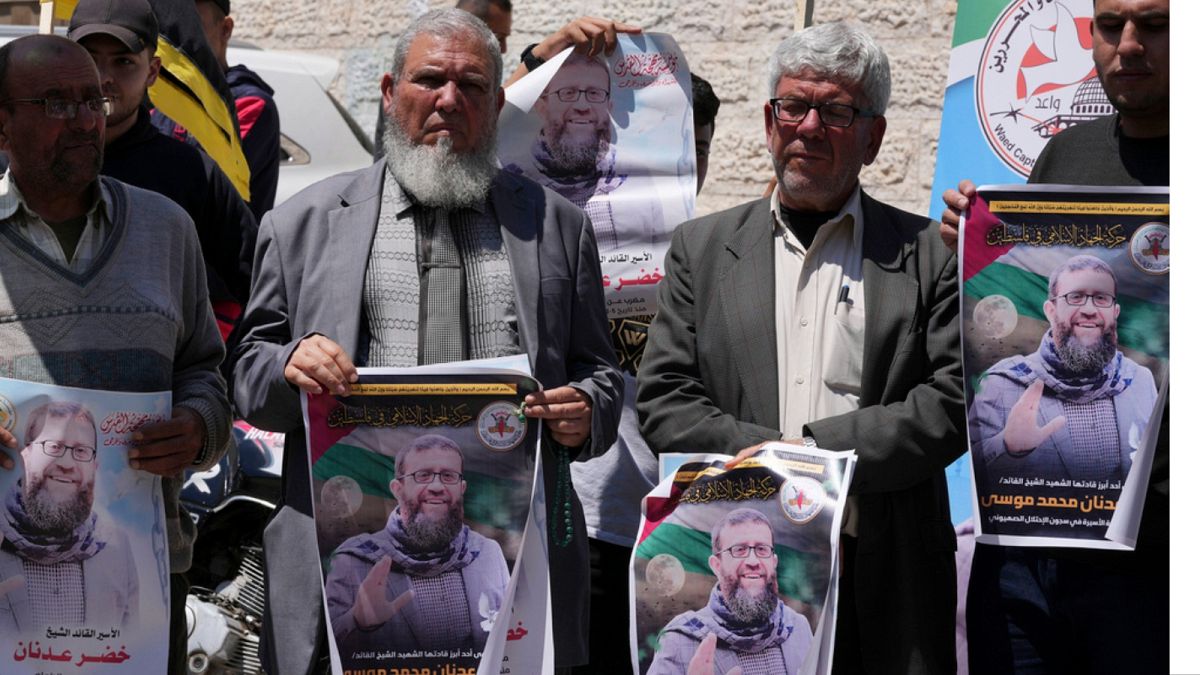 فلسطينيون يحملون صور الأسير خضر عدنان الذي توفي في سجن إسرائيلي، خلال اعتصام أمام مكتب اللجنة الدولية للصليب الأحمر، غزة،  2 مايو 2023.