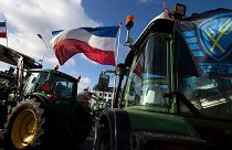 A bandeira da Força de Defesa dos Agricultores, à direita, e as bandeiras holandesas, esvoaçam num cruzamento bloqueado por tractores em Haia, Países Baixos, 19/02/2020