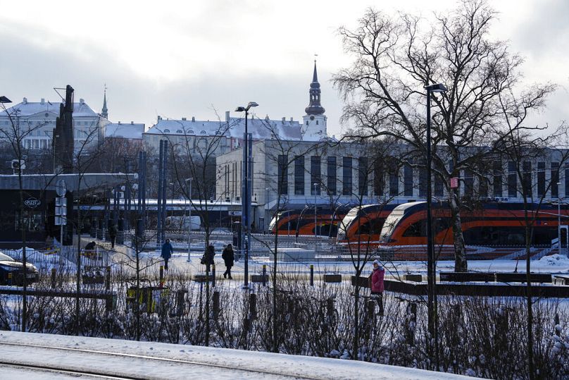 People walk at Baltic train station, with the Stenbock House, left, and St Mary's Cathedral, top, in background, in Tallinn, Estonia.