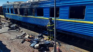 A firefighter stands amidst the debris of a railway carriage hit by Russian shells in Kherson, Ukraine. May 3, 2023.