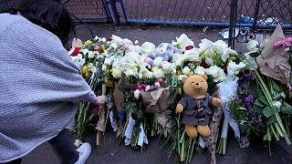 People lay flowers for the victims near the Vladislav Ribnikar school in Belgrade, Serbia, Wednesday, May 3, 2023. 