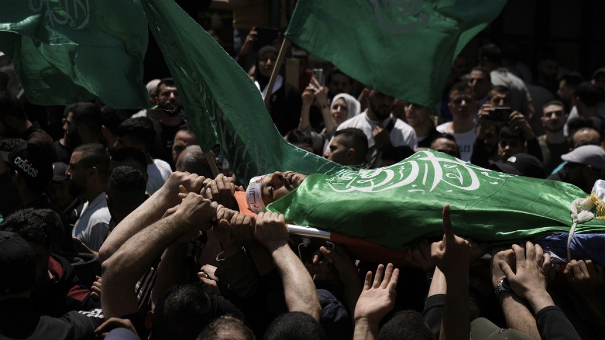 Palestinianos transportam o corpo de Hassan Qatnani, coberto com a bandeira do grupo militante Hamas, durante o seu funeral na cidade de Nablus, na Cisjordânia