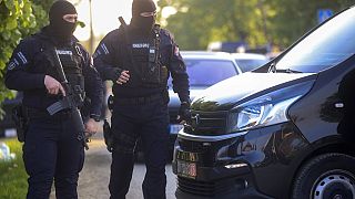 Police officers block the street near the scene of a Thursday night attack in the village of Dubona, south of Belgrade, Serbia, Friday, May 5, 2023.