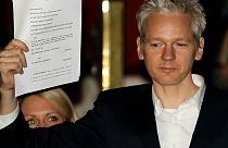 FILE - In this Thursday, Dec. 16, 2010 file photo, WikiLeaks founder Julian Assange holds up a court document for the media after he was released on bail,