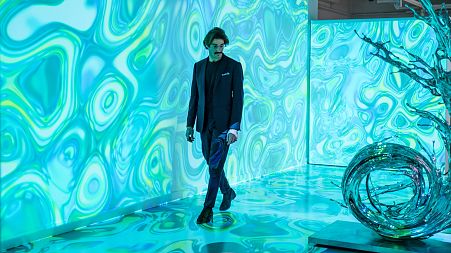 A man walks through the immersive display "Compend AI-XI" by French digital artist Agoria at London's HOFA gallery.