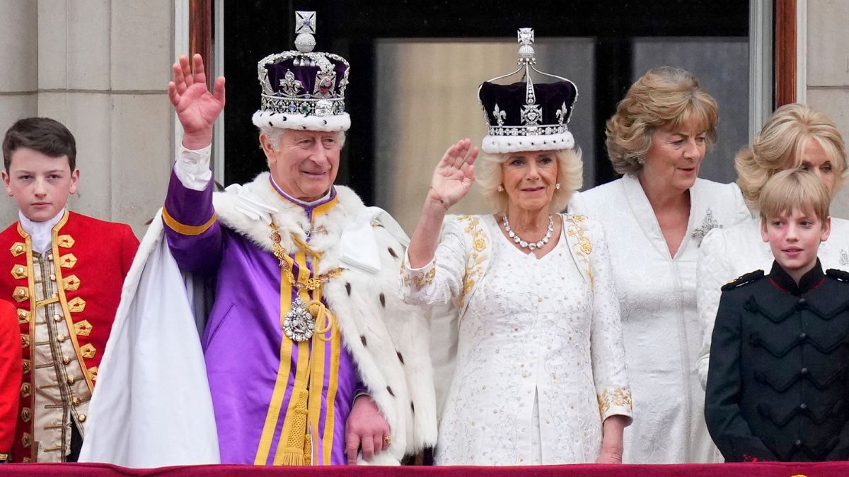 پادشاه بریتانیا به همراه همسرش در بالکن کاخ باکینگهام برای مردم دست تکان می‌دهد
