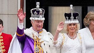 King Charles and Queen Camilla wave from the balcony. 