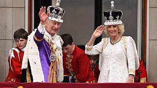 Карл III в Короне Британской Империи и королева Камилла в Короне Марии Текской приветствуют подданных с балкона Букингемского дворца.