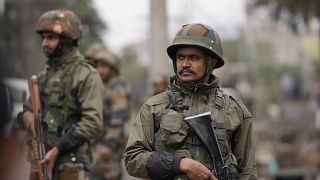 عنصران من الجيش الهندي يتفقدان موقع انفجار في ساحة للسيارات في منطقة ناروال في جامو بالهند