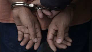 متهم مكبل الأيدي، برفقة الشرطة المدنية الوطنية في سان سلفادور، السلفادور 