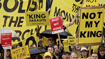 Protesters hold placards as people gather for the coronation of Britain's King Charles III at Westminster Abbey in central London, Saturday, May 6, 2023.