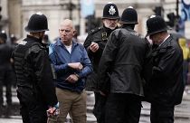 عناصر من الشرطة البريطانية تلقي القبض على مشارك خلال مراسيم تتويج تشارلز الثالث في لندن، بريطانيا.