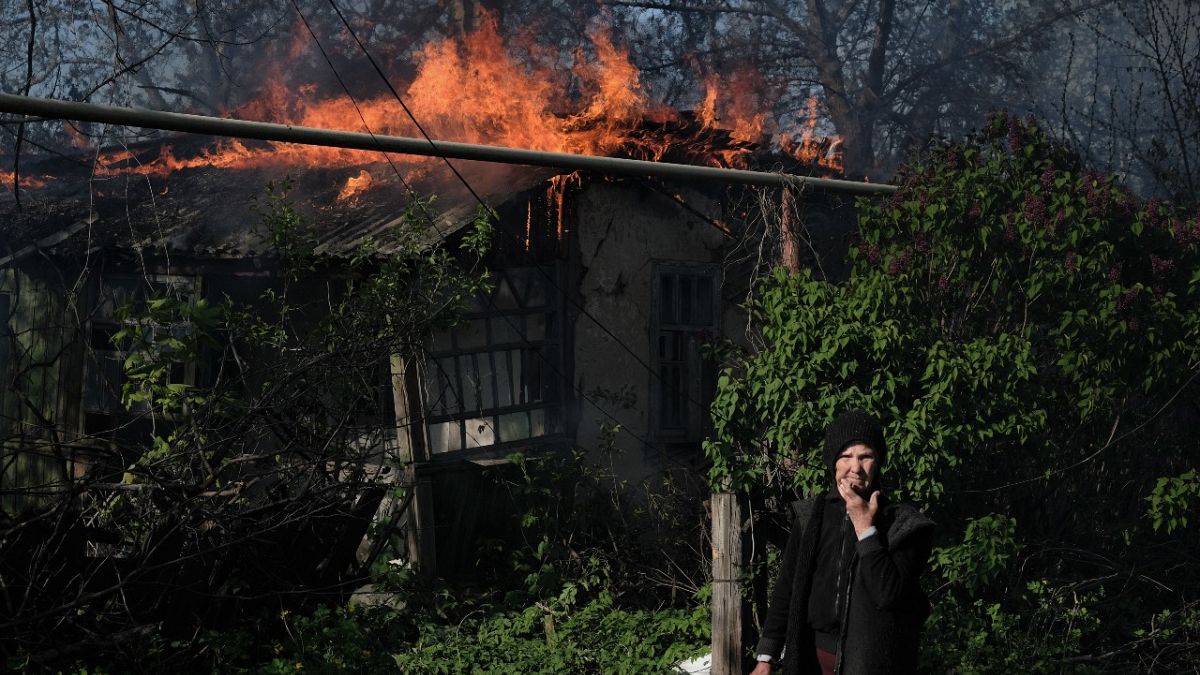 Idős asszony egy égő ház előtt a donyecki bombázások után május 7-én