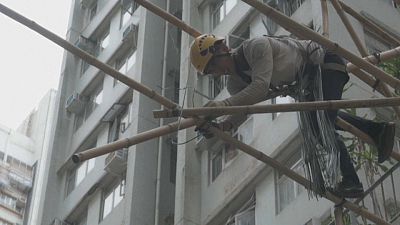Ein Arbeiter verbindet zwei Bambusstangen eines Baugerüsts.