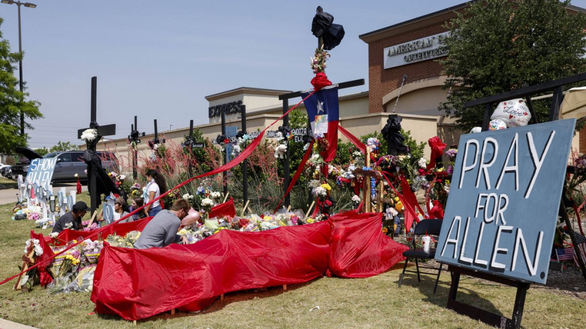 People place flowers and pay their respects at a memorial for victims of the Allen Premium Outlets mass shooting