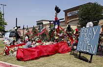 People place flowers and pay their respects at a memorial for victims of the Allen Premium Outlets mass shooting
