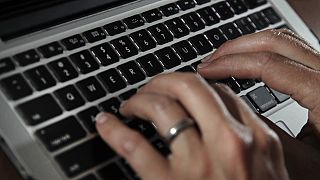 A person types on a laptop keyboard 