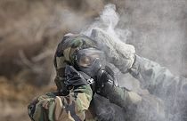 A solider tries to clean off mock chemical pollutants in a drill. 