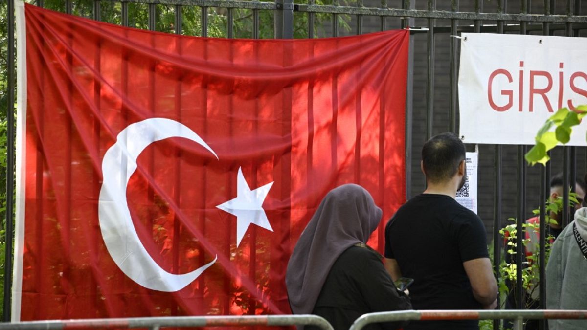 Turkish voters pass a Turkish flag as they make their way to the polling station at the Turkish consulate in Berlin on May 9, 2023. 