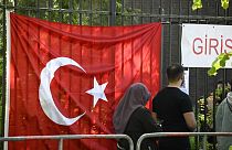 Turkish voters pass a Turkish flag as they make their way to the polling station at the Turkish consulate in Berlin on May 9, 2023. 