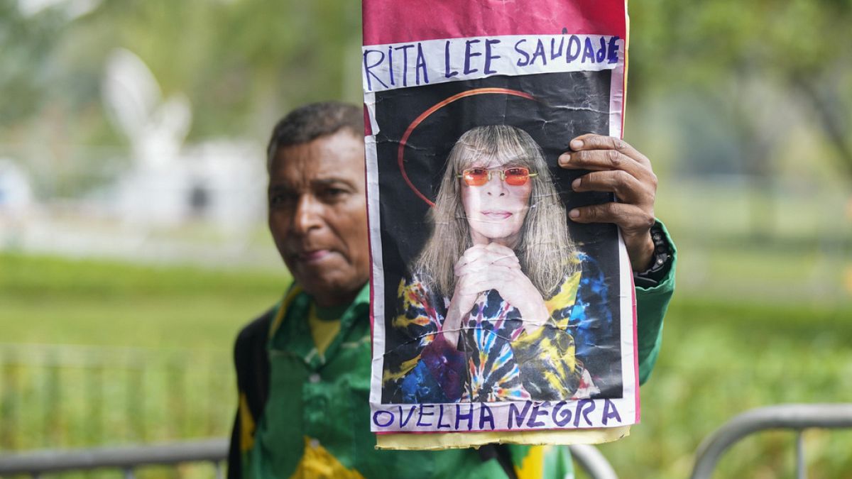A fan in Sao Paulo holds up a photo of Rita Lee with one of her best-known hits written on it.
