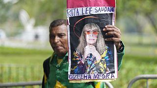 A fan in Sao Paulo holds up a photo of Rita Lee with one of her best-known hits written on it.