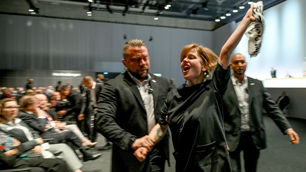 Climate activists are taken out of the venue of the annual shareholders' meeting of the Volkswagen AG in Berlin.