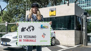 Активистка с плакатом "Увидимся в суде" возле "Палаццо Эни" в Риме.