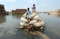 Victims of catastrophic flooding in Pakistan use a makeshift barge to carry hay for cattle in Jaffarabad, September 2022.