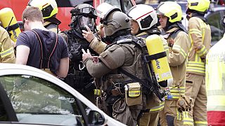 Police officers wearing gas masks and firefighters stand in front of a residential building in Ratingen, Germany, Thursday May 11, 2023. 