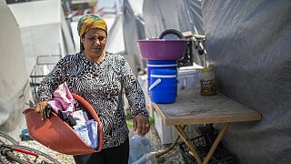 Hatice Onlen brings her laundry next to tents where she and her family temporarily live after a powerful earthquake in Antakya, southeastern Turkey, Wednesday, May 10, 2023.