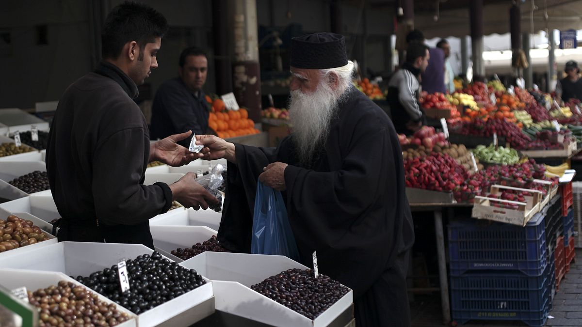 Ein Priester kauft Oliven auf einem Markt in Athen