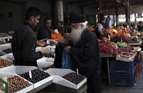 Ein Priester kauft Oliven auf einem Markt in Athen
