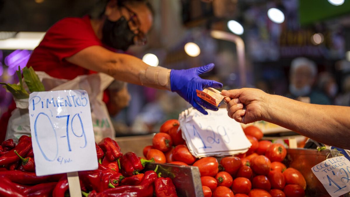 A customer pays for vegetables at the Maravillas market in Madrid, Thursday, May 12, 2022. 