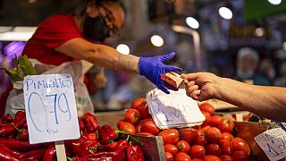 A customer pays for vegetables at the Maravillas market in Madrid, Thursday, May 12, 2022.