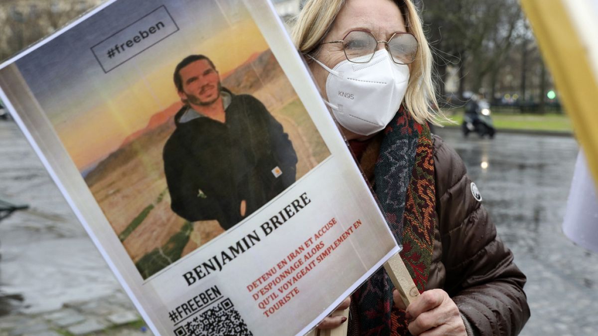 Mulher segura um cartaz com a foto de Benjamin Brière, durante manifestação pela sua libertação, a 08 de janeiro de 2022, em Paris, França