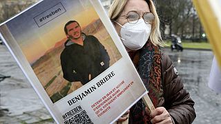 پرونده - زنی عکسی از بنجامین بریر را در حین تظاهرات در پاریس، فرانسه، شنبه، 8 ژانویه 2022 در دست دارد. 