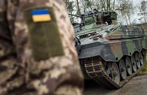 A Ukrainian soldier is standing in front of a Marder infantry fighting vehicle at the German forces Bundeswehr training area in Munster, Germany