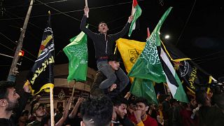 Palestinians celebrate the announcement of a cease-fire after five days of fighting