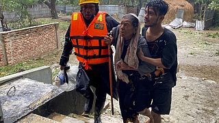 Rescue workers help an elderly woman to reach a makeshift shelter after a storm in Teknaf, near Cox's Bazar, Bangladesh, Sunday, May 14, 2023.