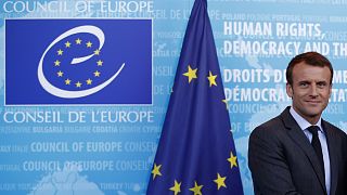 Emmanuel Macron, presidente de Francia ante un logo del CoE