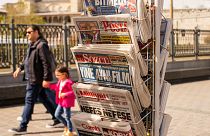 People walk past a rack with Turkish newspapers a day after the presidential election day, in Istanbul, Turkey, Monday, May 15, 2023.
