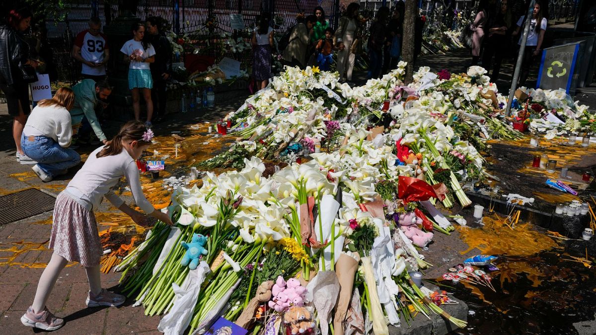 A girl lays flowers for the victims in front of the Vladimir Ribnikar school, after a 13-year-old boy used his father's guns to kill eight fellow students and a guard