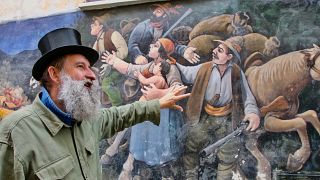 Giovanni Casale explains one of the hundreds of murals present in Valogno 