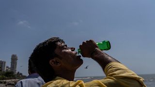 Мальчик пьет газировку на набережной в Мумбаи, Индия