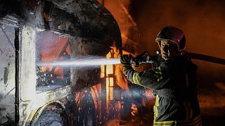 firefighter tries to put out fire caused by fragments of a Russian rocket after it was shot down by air defense system during the night Russian rocket attack in Kyiv, Ukraine,