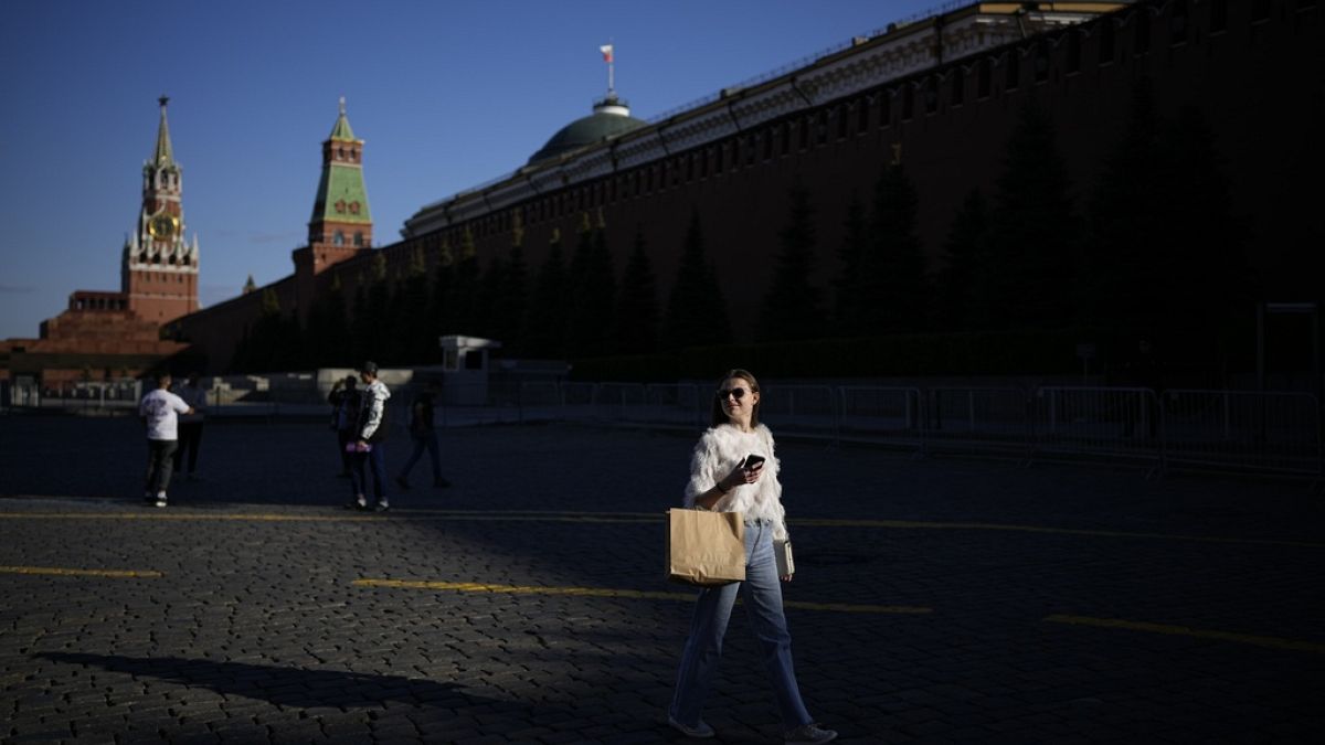 A woman walks in Red Square enjoying warm weather during sunset with the Kremlin Wall in background in Moscow, Russia, May 16, 2023