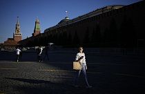 A woman walks in Red Square enjoying warm weather during sunset with the Kremlin Wall in background in Moscow, Russia, May 16, 2023